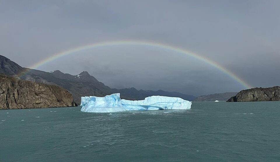 Ein Eisberg auf dem Lago Argentino unter einem Regenbogen.