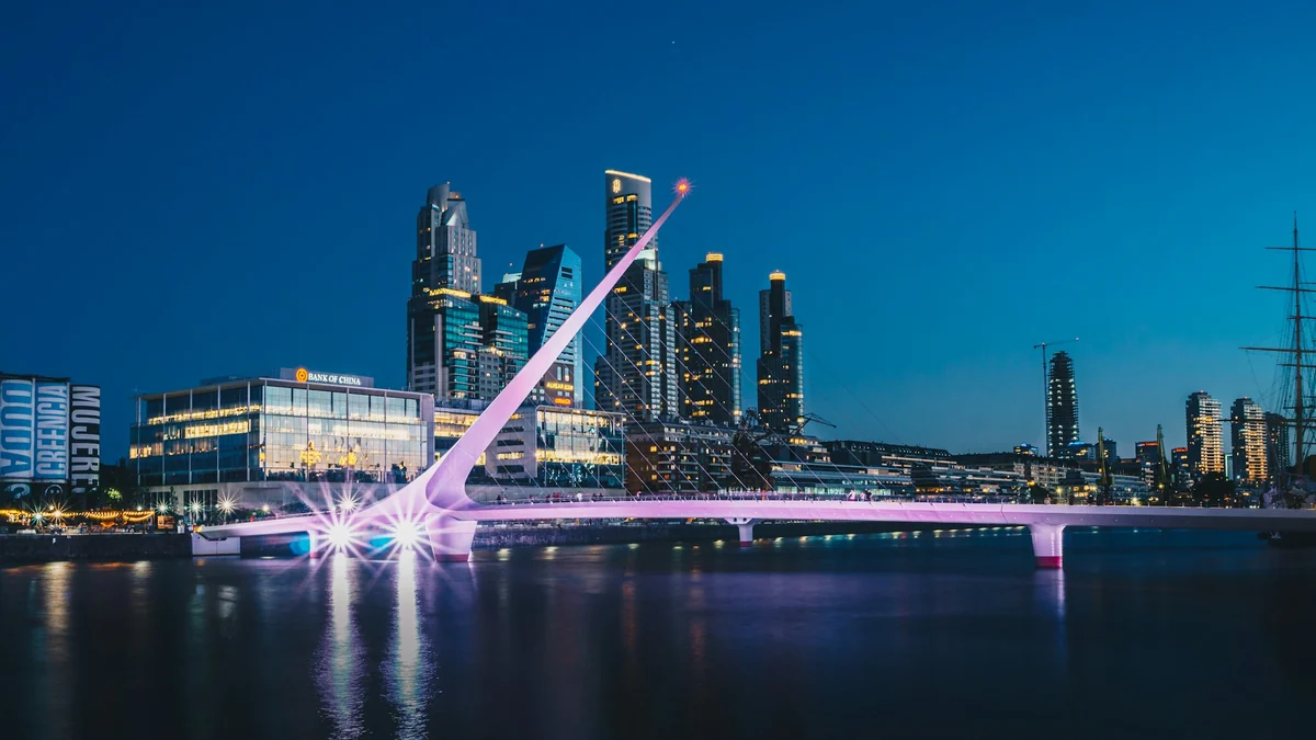 Beleuchtete Puente de la Mujer vor den Hochhäusern von Puerto Madero zur blauen Stunde.