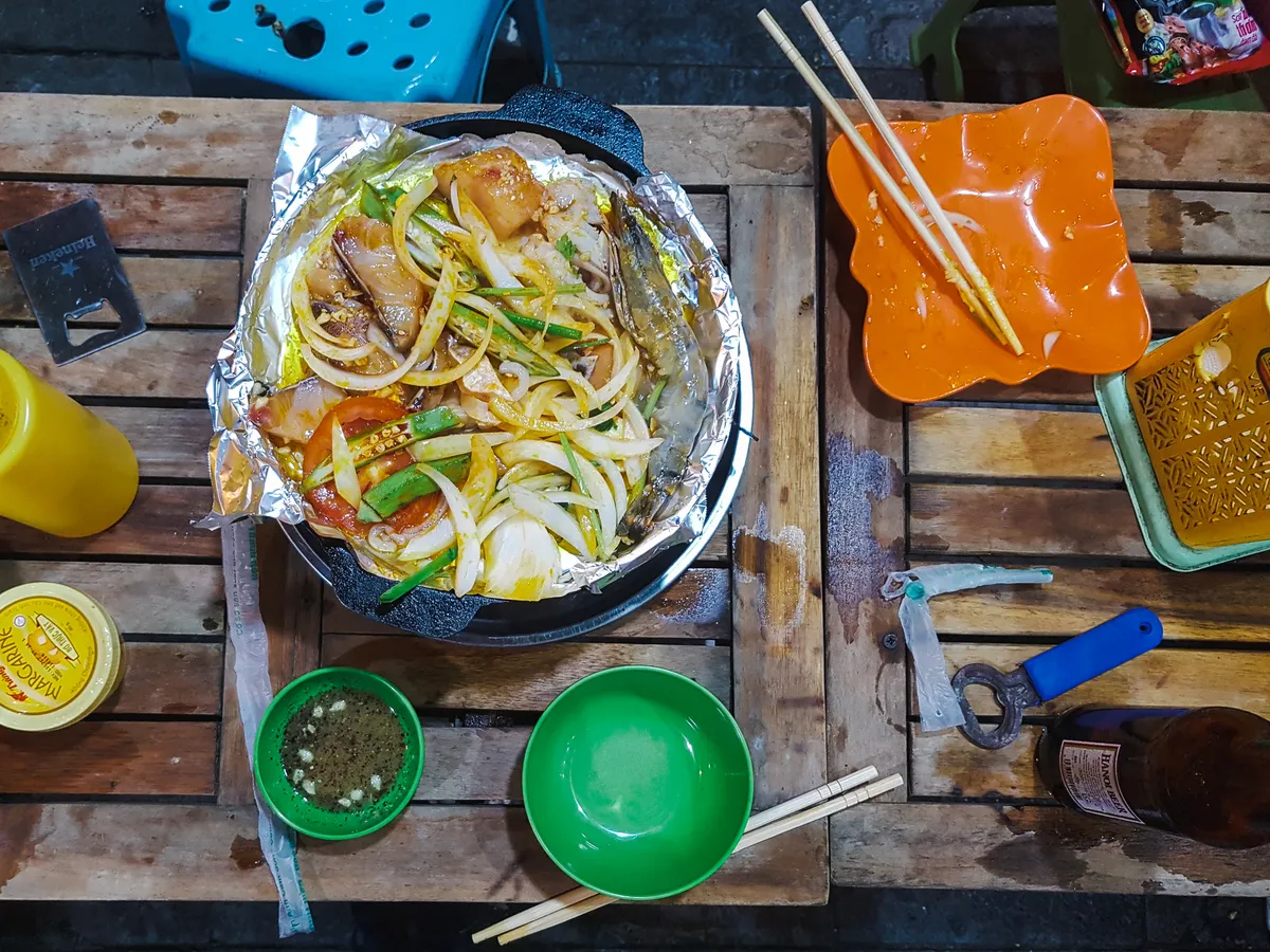 Gegrillter Fisch und Meeresfrüchte auf einem heißen Stein in einem Straßenlokal von Hanoi